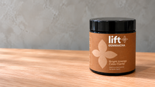 Lift Genmaicha black jar on the right of a wooden tabletop with space beside it